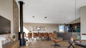 Una sala de estar moderna con chimenea, comedor y cocina.