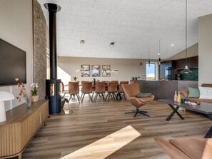 Una sala de estar moderna con chimenea, comedor y cocina.