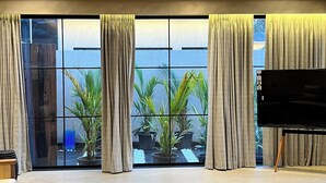 Un salón amplio con un gran ventanal, un ventilador de techo y un televisor de pantalla plana negro.