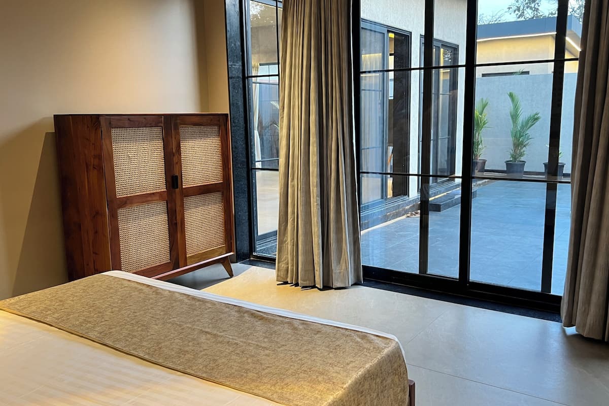 Een hotelkamer met een bed, een houten kast en grote ramen met gordijnen.