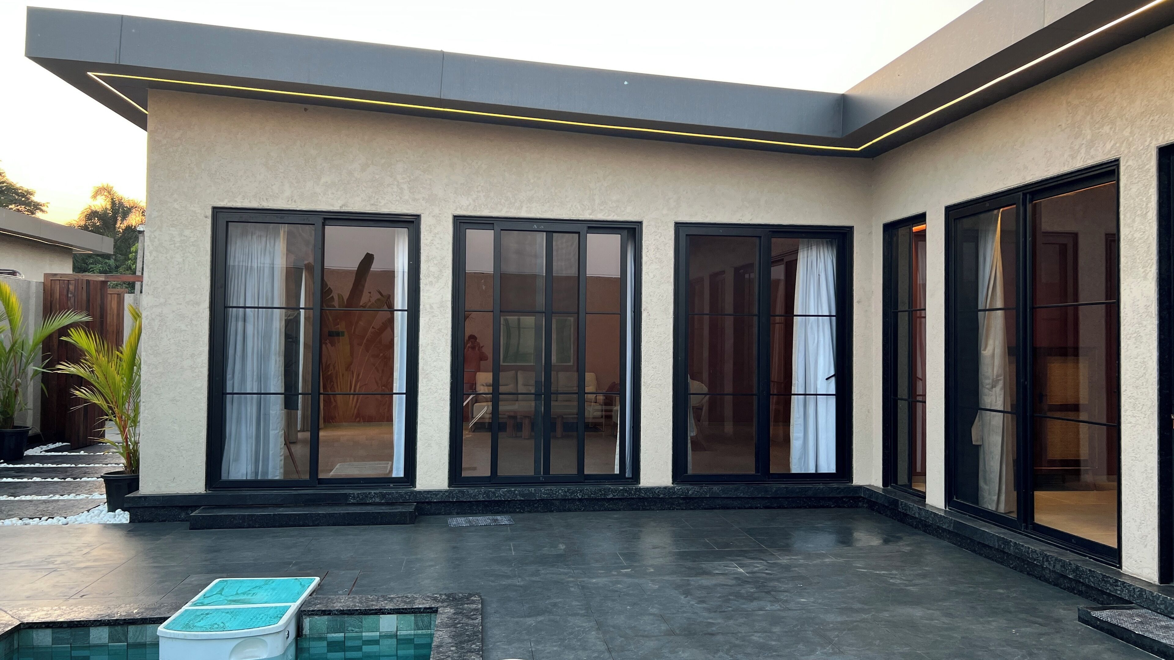 Uma casa moderna com piscina, amplas portas de vidro deslizantes e uma área de varanda coberta.