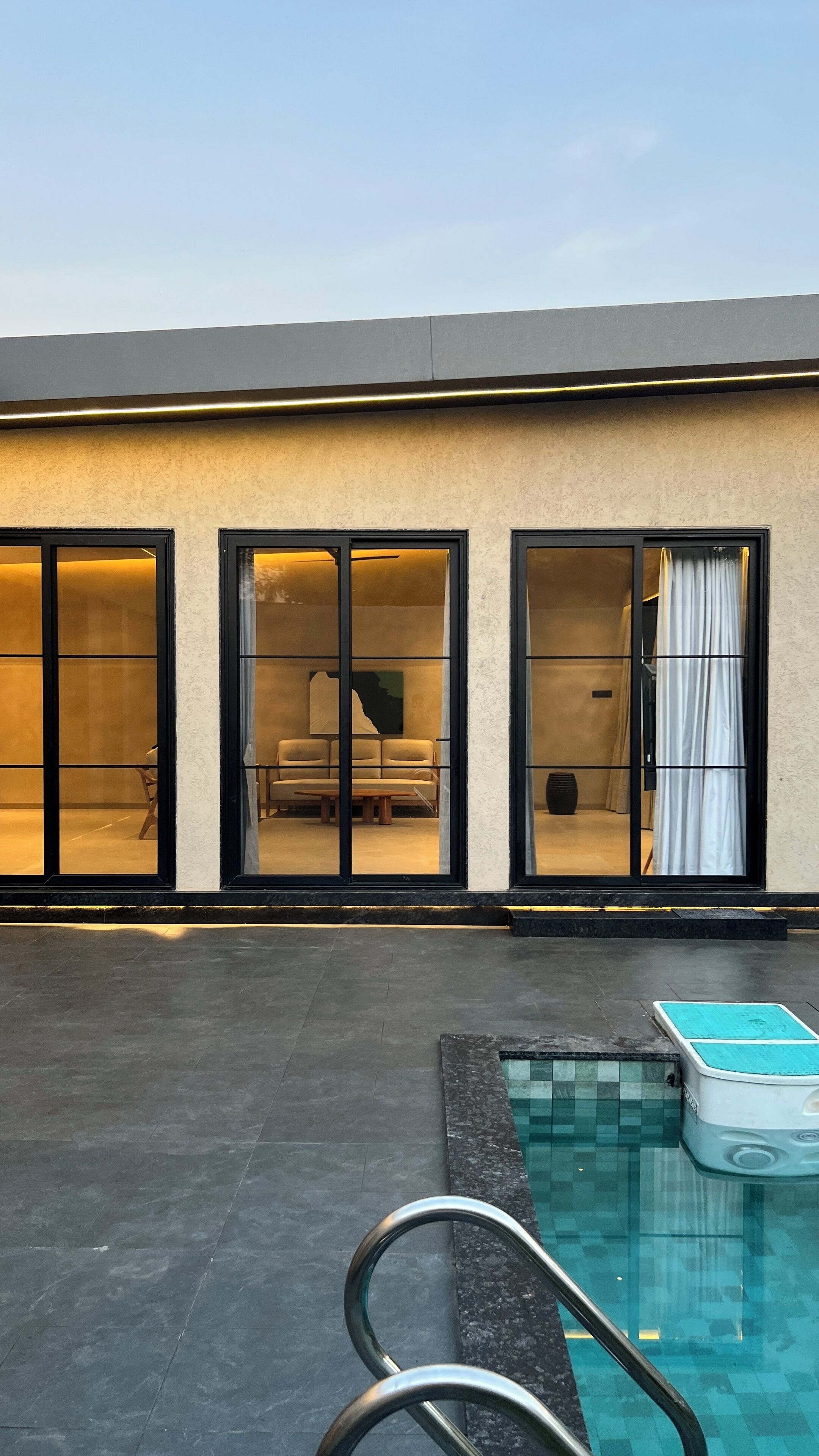 A modern building with large glass doors leading to a pool area.