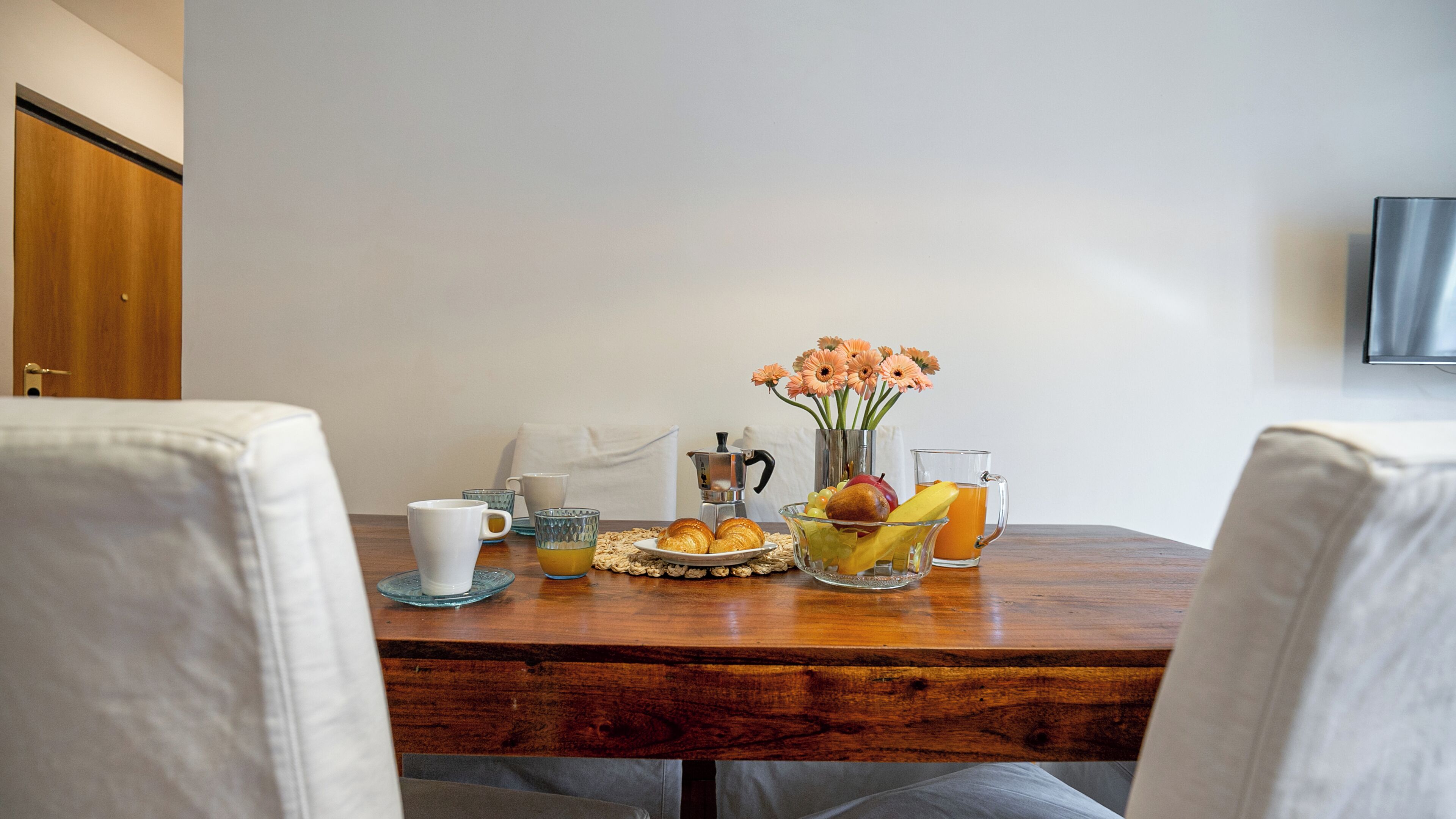 Een ontbijttafel met diverse lekkernijen, zoals croissants, fruit en een koffiepot.