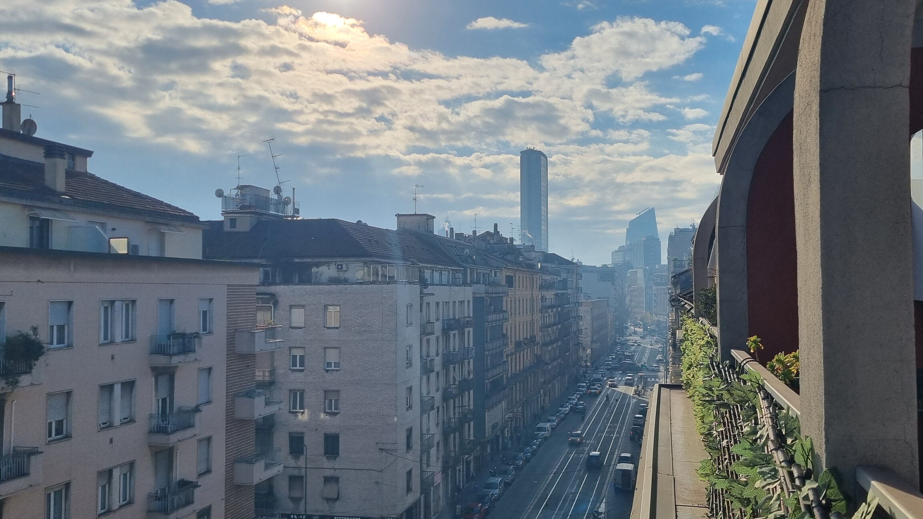 A cityscape with multi-story buildings, a busy street, and a clear sky.