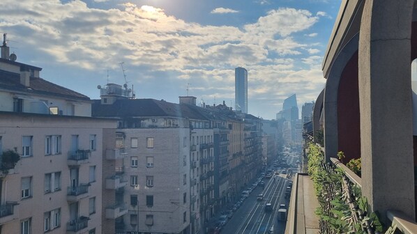 Un paisaje urbano con edificios de varios pisos, una calle concurrida y un cielo despejado.