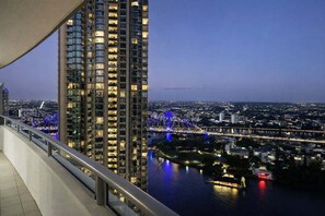 Un immeuble de grande hauteur offrant une vue sur le paysage urbain et un pont, de nuit.