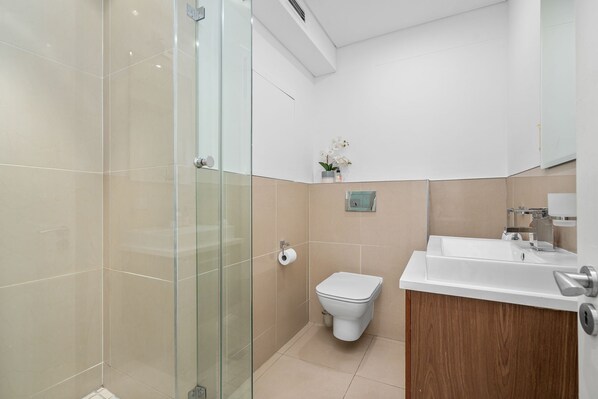 Une salle de bain moderne avec une douche à parois de verre, des toilettes et un lavabo avec un meuble en bois.