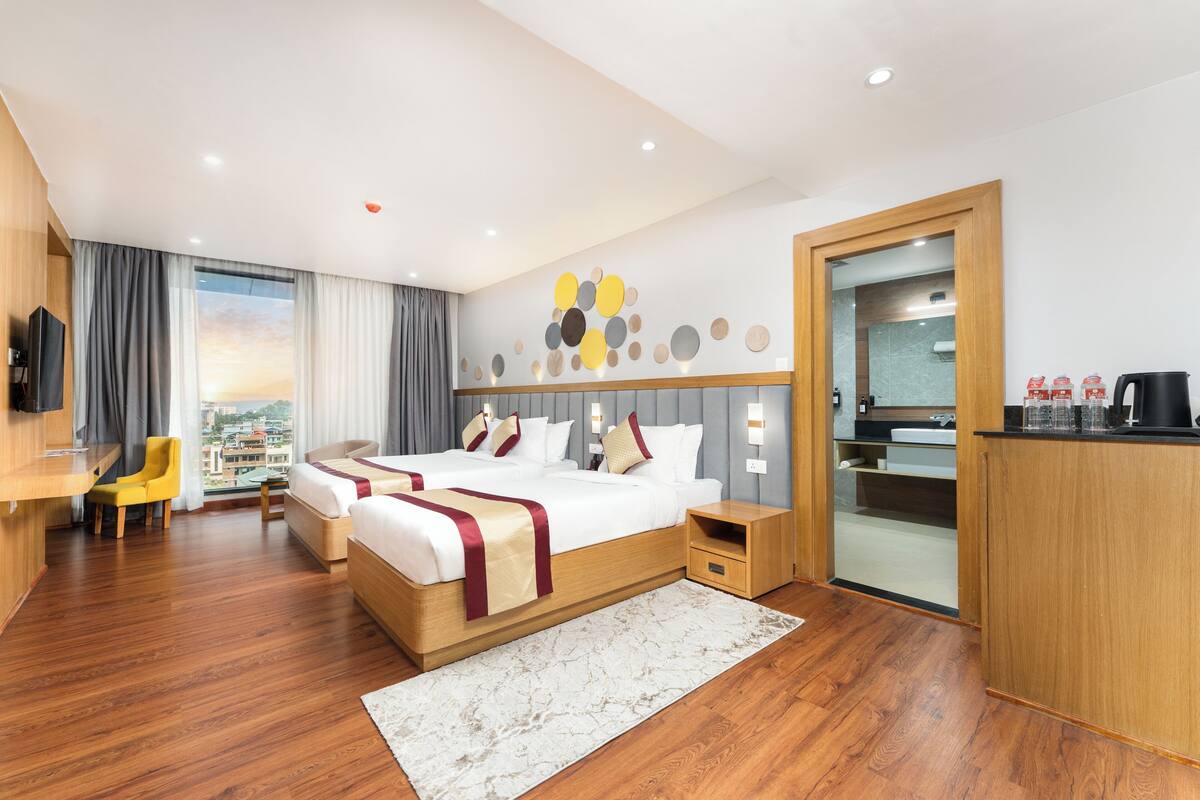 Une chambre d’hôtel avec un grand lit, un bureau, une chaise, une télévision et une vue sur la ville.