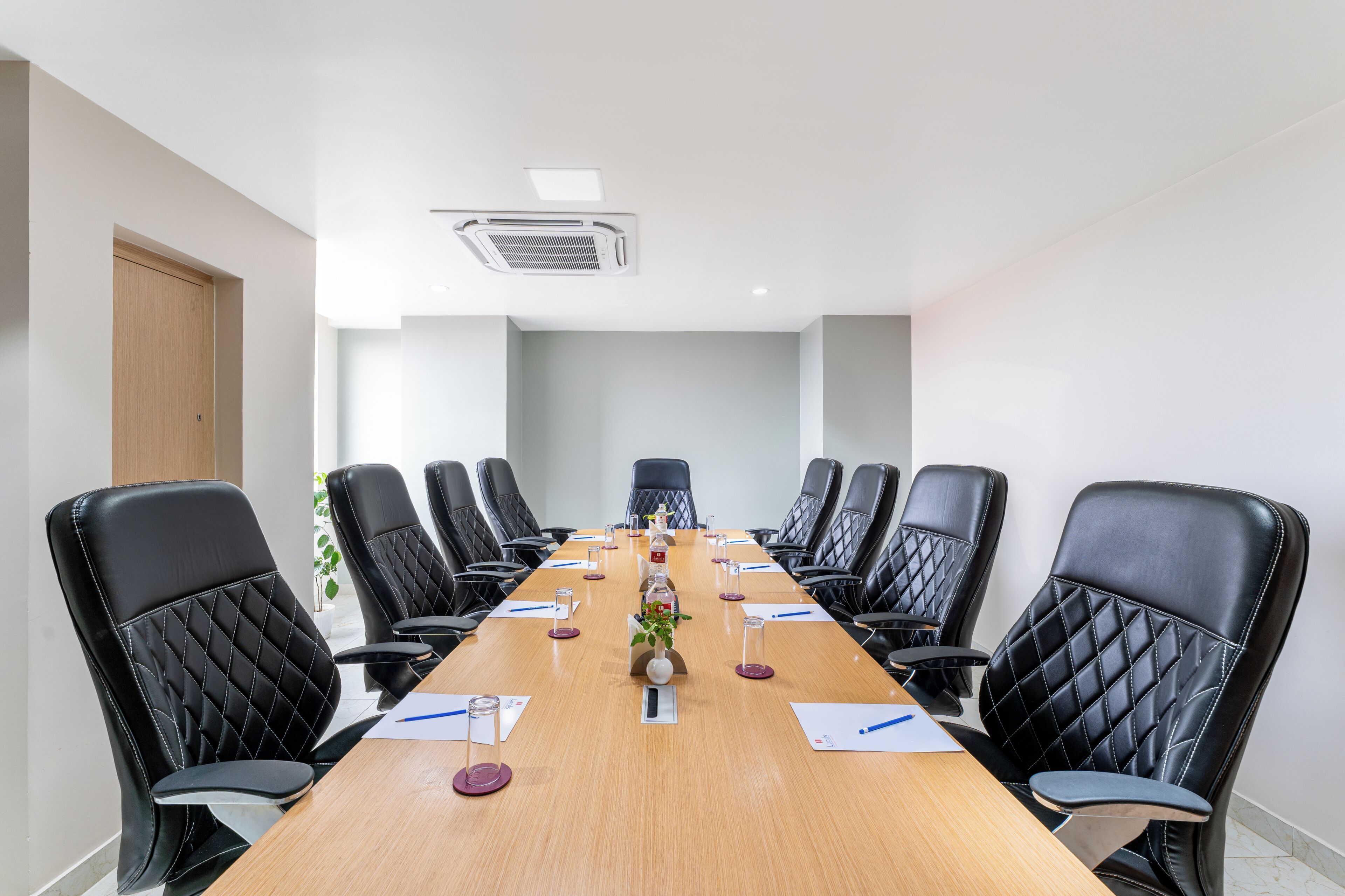 A conference room with a long table, black leather chairs, and a whiteboard.