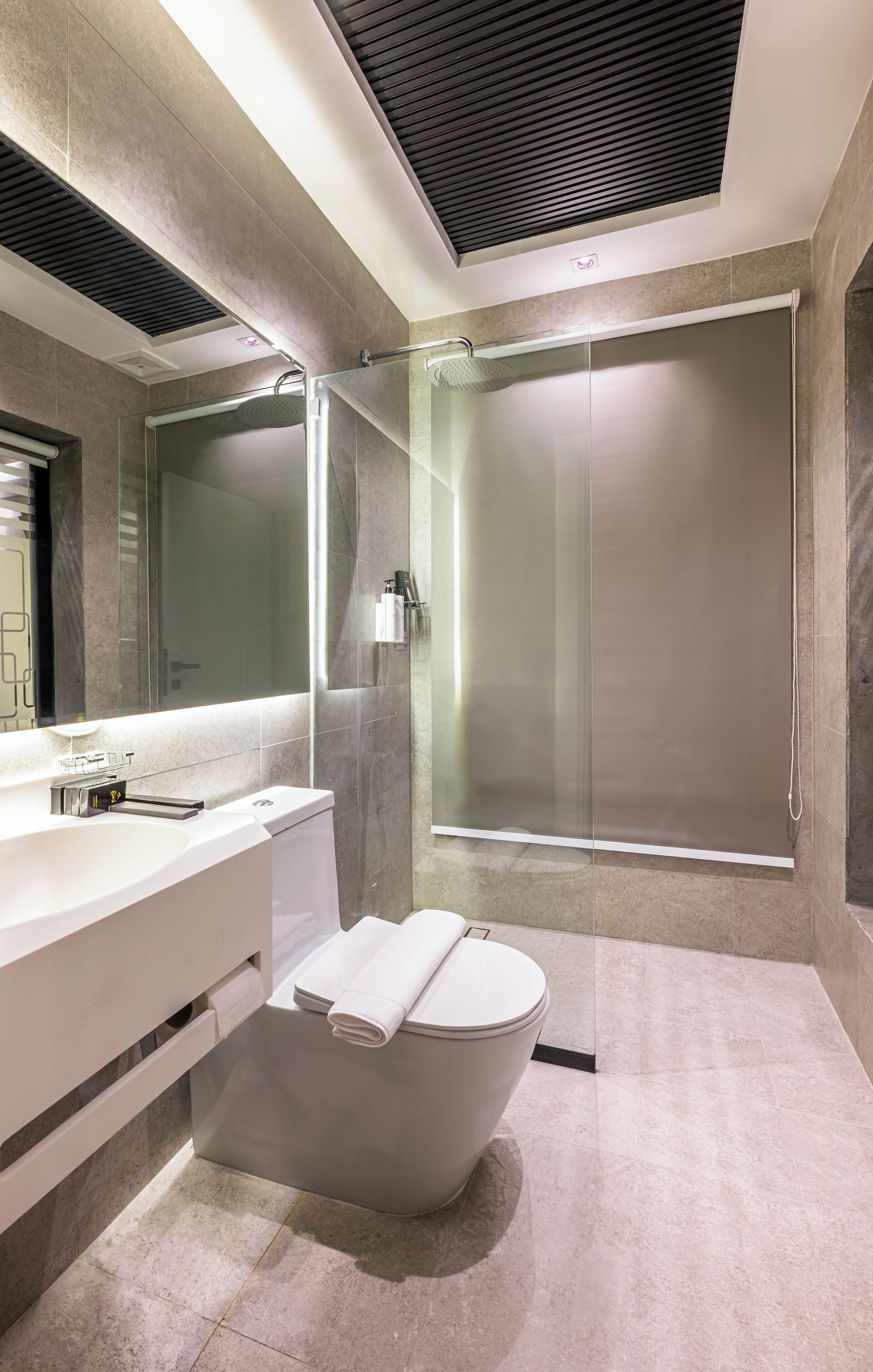 Un baño moderno con ducha envuelta en vidrio, lavamanos blanco y un inodoro.