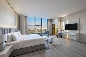 A modern hotel room with a large bed, a desk, a TV, and a city view. - Karim Hotel  (Dammam)