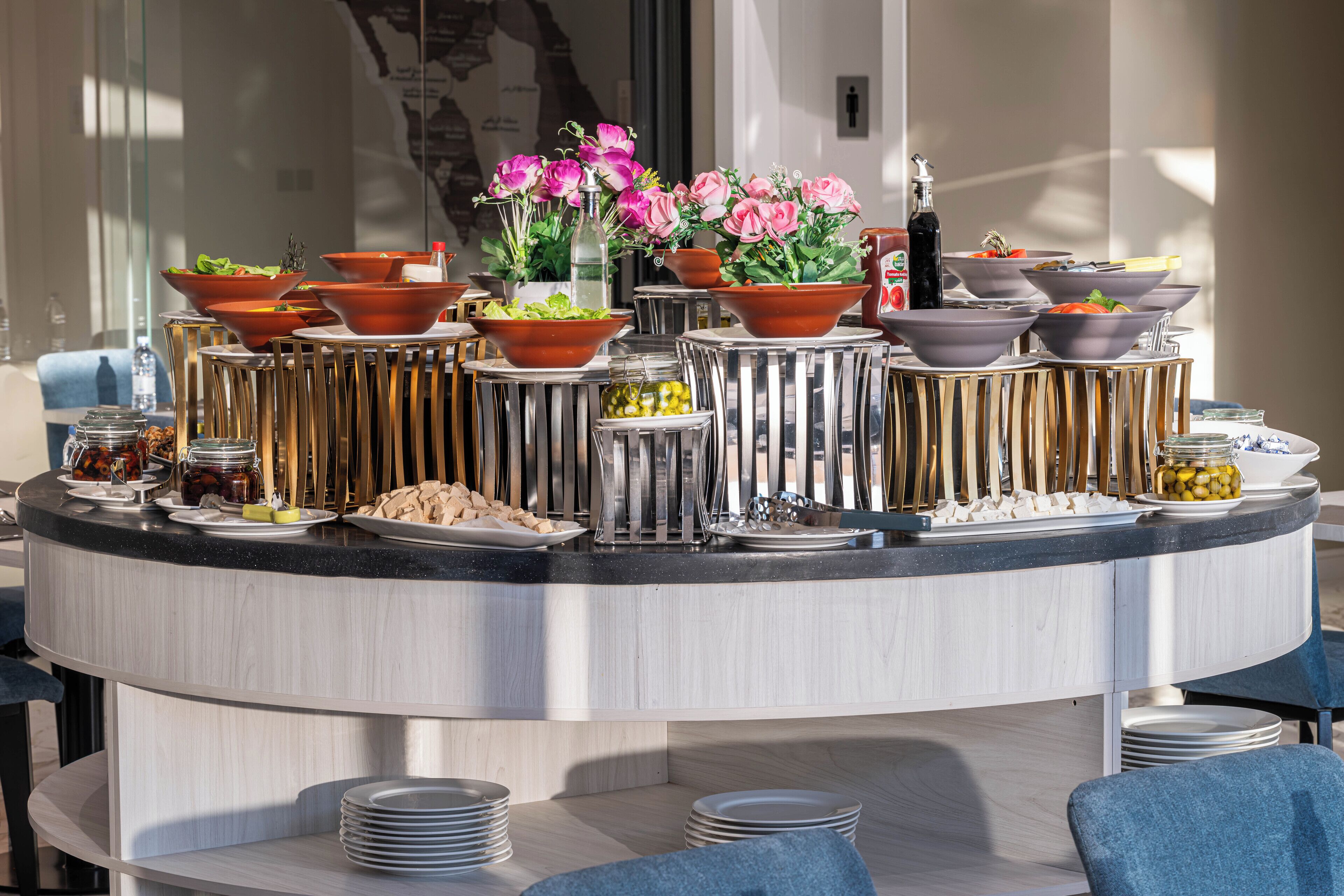 A buffet setup with various food items, serving dishes, and decorative flowers.