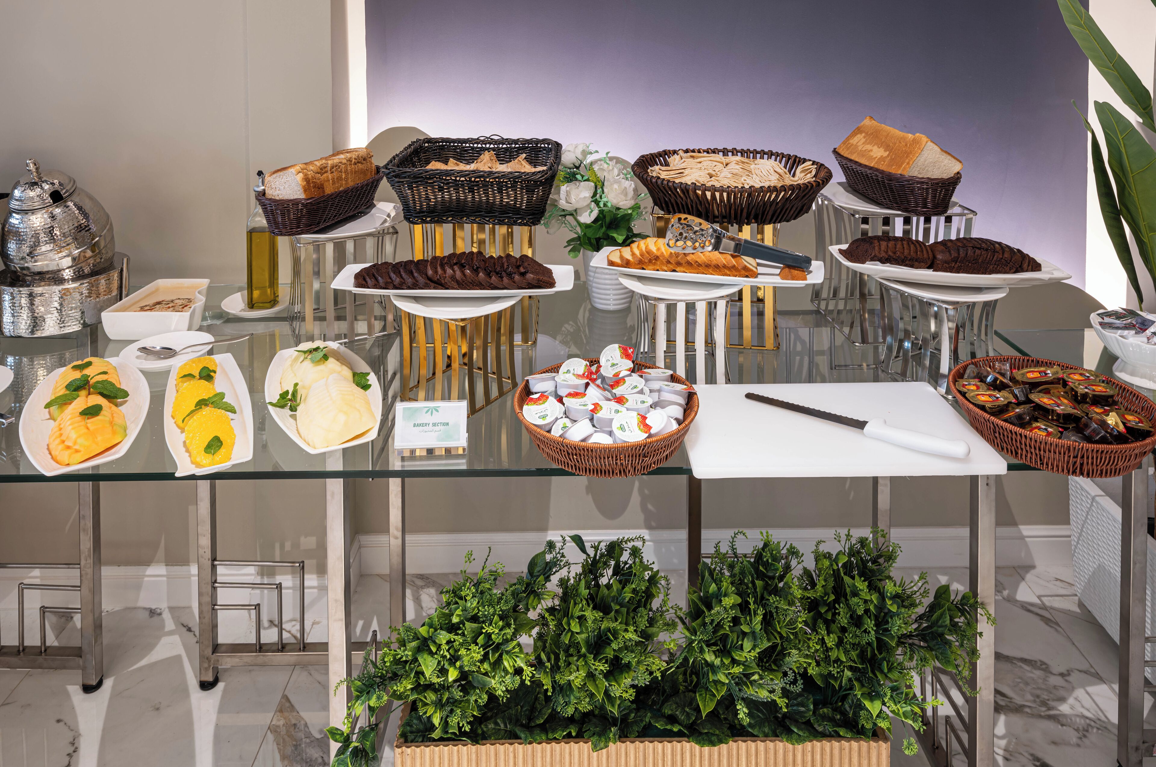 Una mesa de buffet con diversos alimentos, como pan, pasteles y un cuchillo sobre una tabla de cortar.