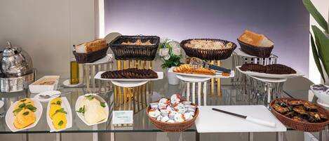 Een buffettafel met diverse gerechten, waaronder brood, gebak en een mes op een snijplank.