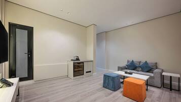 A modern living room with a sofa, ottoman, coffee table, and a small cabinet.
