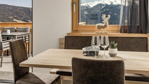 Ein Essbereich mit Holztisch, gepolsterten Stühlen, einem Fenster mit Bergblick und einer Rentiierdekoration.