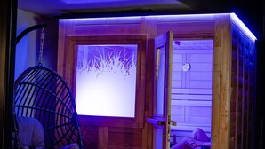 Uma sauna de madeira com porta de vidro, uma cadeira suspensa e um banco de sauna à vista.