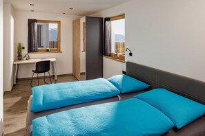 A bedroom with two beds, a desk, and a chair.