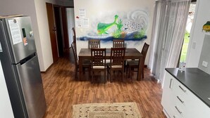 A kitchen with a dining table, chairs, a refrigerator, and a wall mural. - HESPS OF BEDS (South West Rocks)