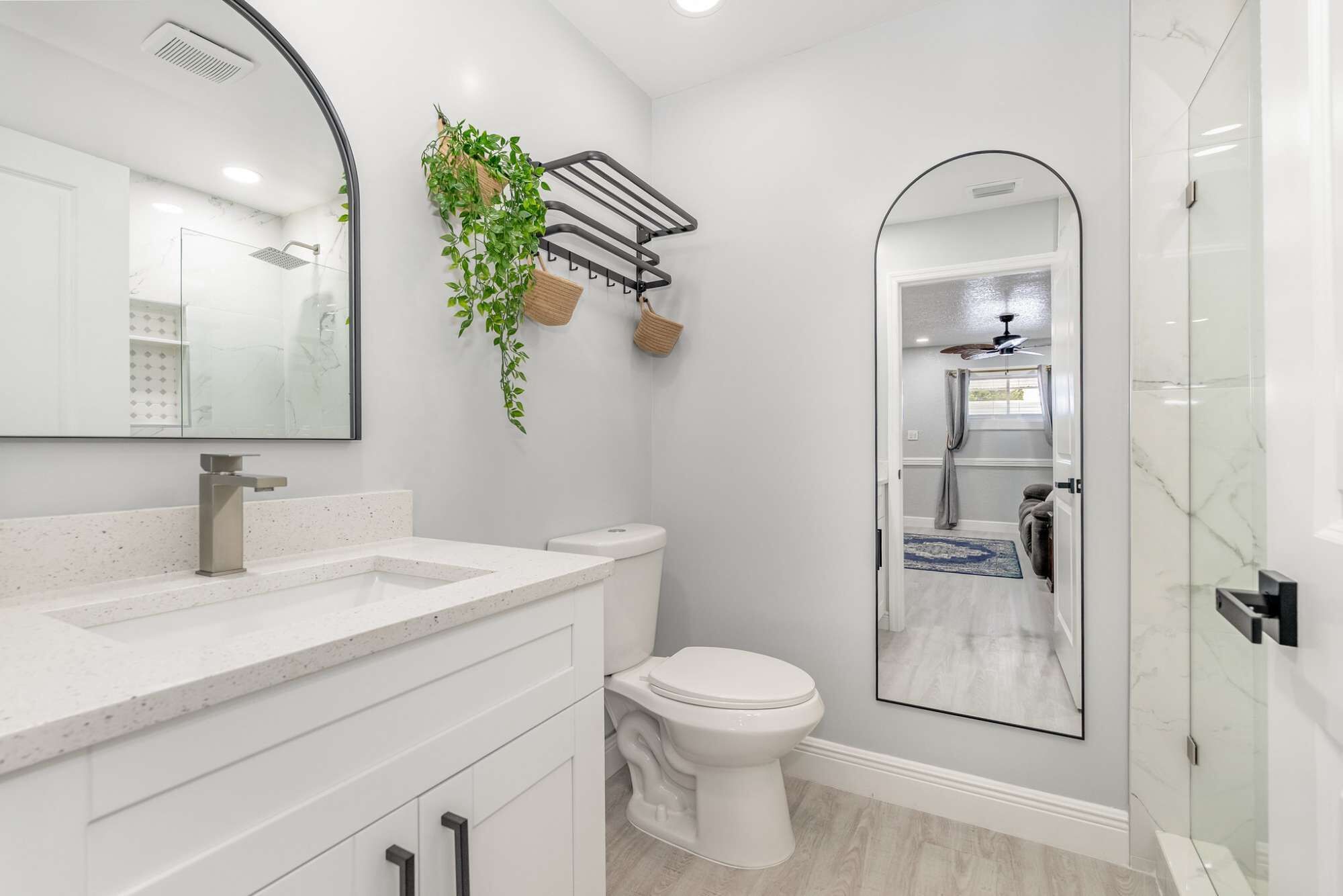 A modern bathroom with a glass shower enclosure, a white toilet, and a large mirror.
