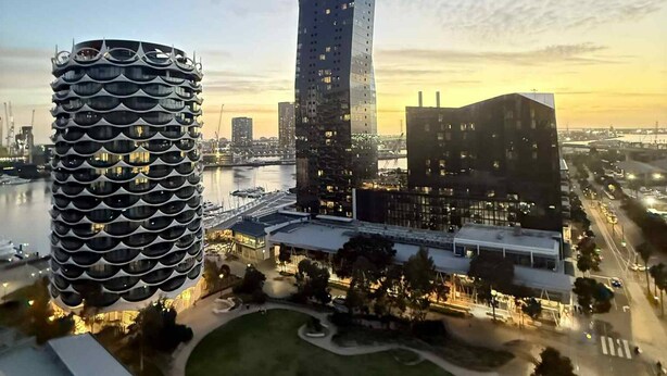 A modern cityscape with a distinctive cylindrical building and a tall skyscraper. - Cosy 2 Bedroom Apartment With Pool, gym and Sauna (Melbourne)