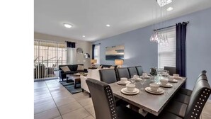 A modern dining area with a rectangular table set for six, surrounded by black upholstered chairs. - Spacious 7 BR Villa with Pool, Spa, Themed Rooms (Kissimmee)