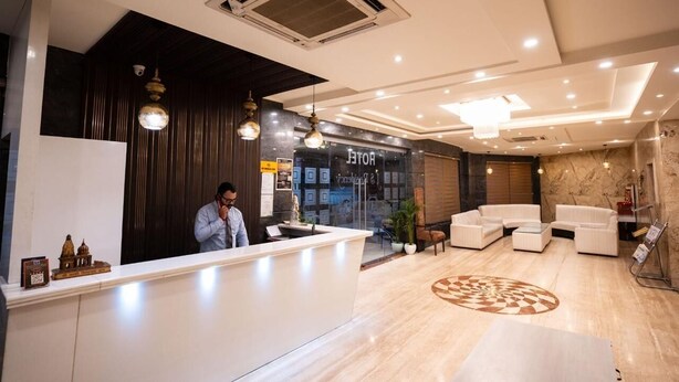 A hotel reception area with a modern design, featuring a reception desk, seating area, and a large decorative floor pattern. - JS Residency (Varanasi)