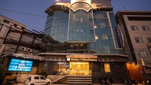 A modern hotel with a prominent entrance, a staircase leading to the lobby, and a large digital sign advertising the hotel. - JS Residency (Varanasi)