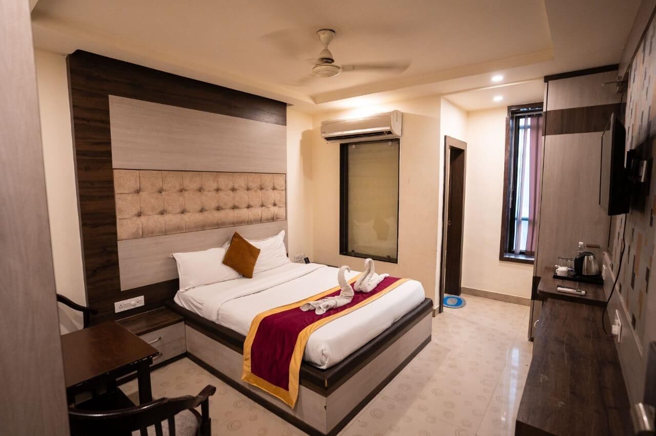 A hotel room with a bed, a desk, a chair, a TV, and a wardrobe.