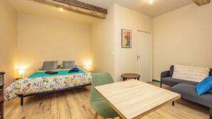Una camera accogliente con un letto, una poltrona, un tavolino e una sedia.