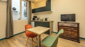 Una cucina compatta con un tavolo da pranzo, due sedie, una televisione e un armadietto in legno.