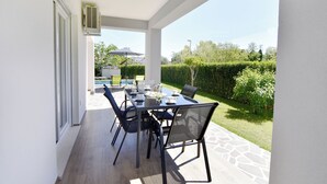 Eine Terrasse im Freien mit einem Essplatz und Stühlen drumherum.