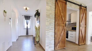 Ein modernes Interieur mit Holzboden, einer Küchenzeile mit weißen Schränken und einer Schiebetür im Scheunenstil.