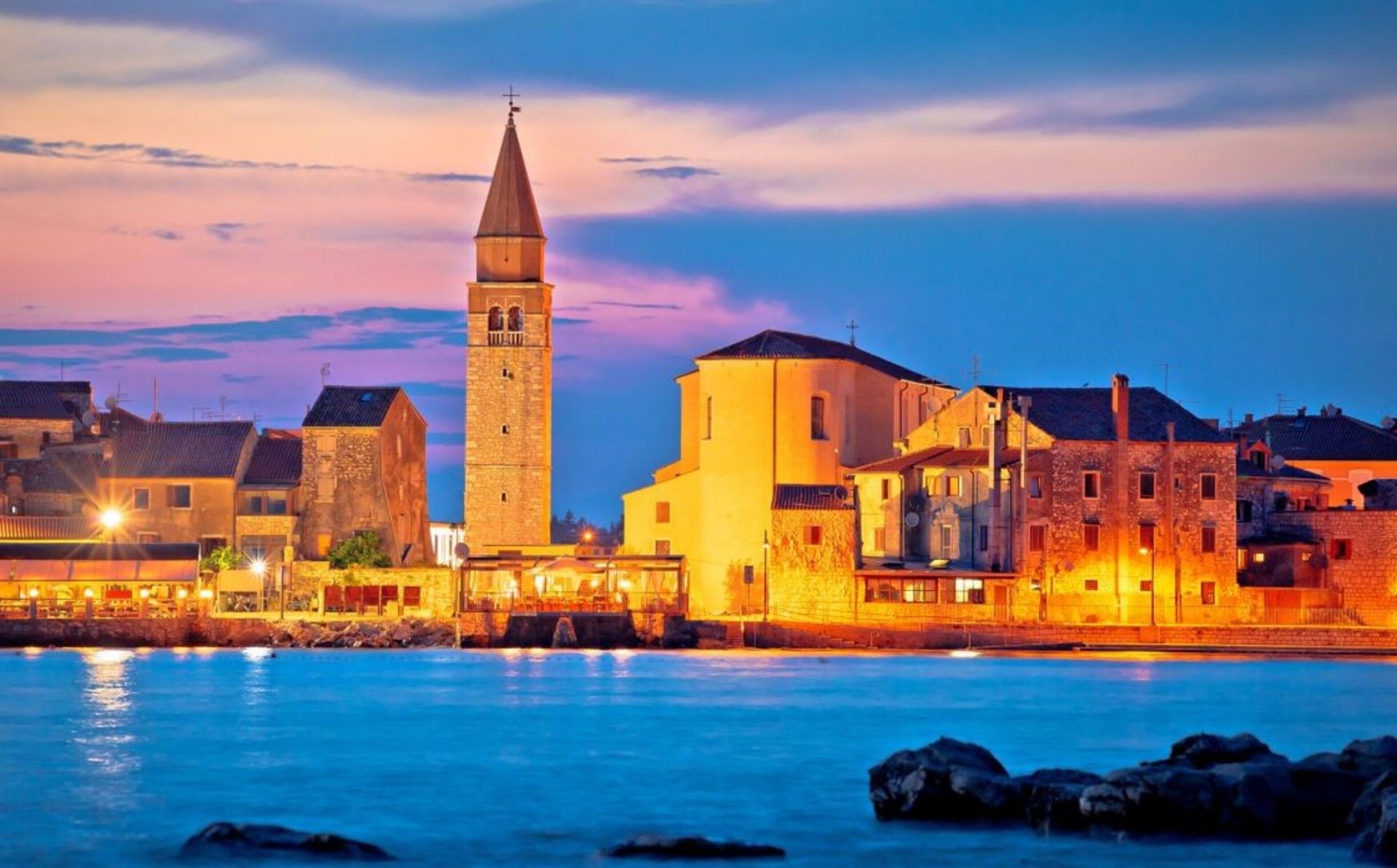 A coastal town with a prominent tower and stone buildings, likely a historic site with waterfront views.