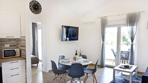 A modern dining area with a round table, chairs, and a small side table. A flat-screen TV is mounted on the wall above the table. - Modern holiday home with shared pool (Čepljani)