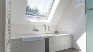 Ein modernes Badezimmer mit Oberlicht, Badewanne und Dusche.