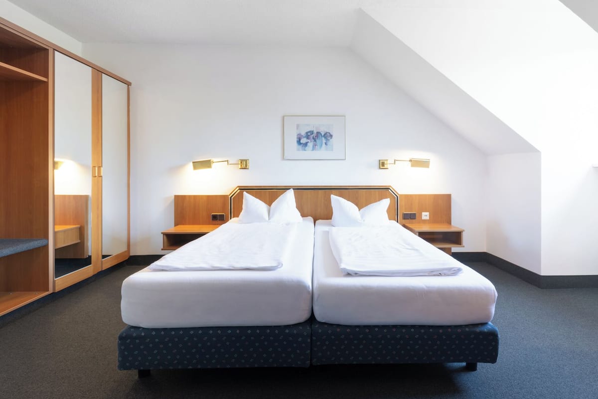 Une chambre d’hôtel avec un lit double, deux tables de chevet, une armoire et un tableau au mur.