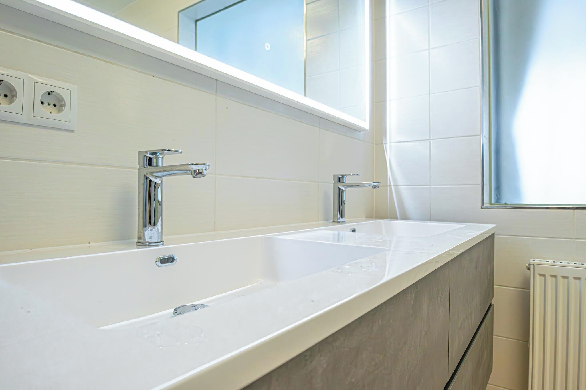 A bathroom with two sinks, a mirror above the sinks, and a window.