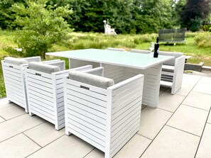Eine helle, begrünte Terrassenanlage mit Tisch und Stühlen.