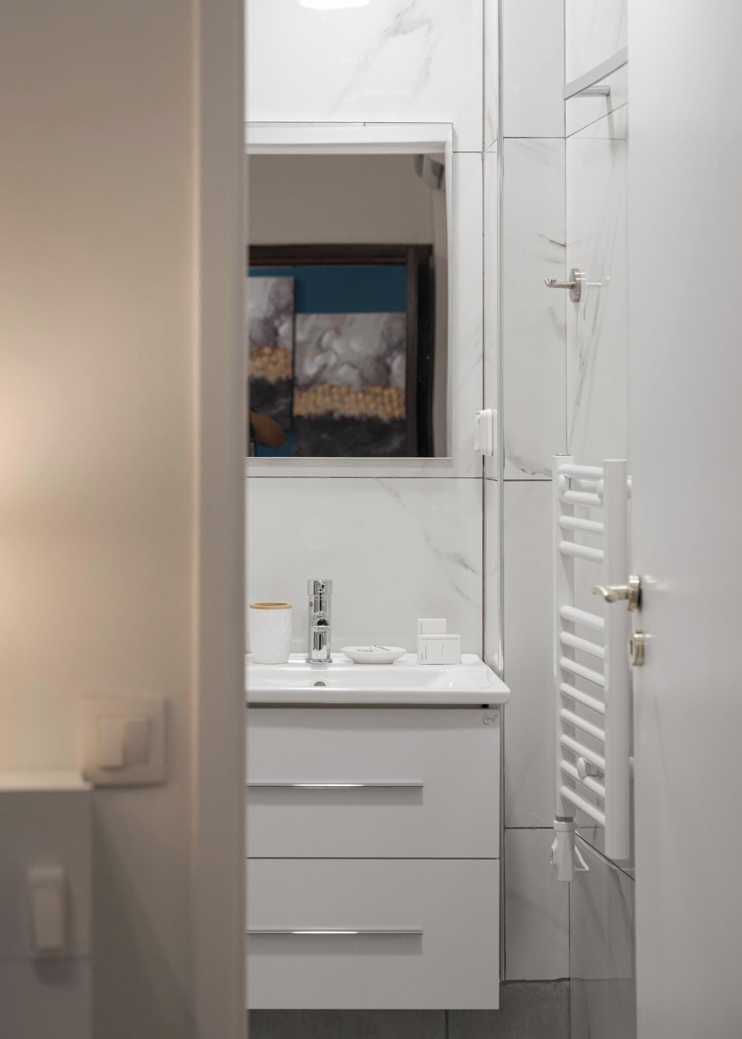A modern bathroom with a white vanity, a mirror, and a radiator.