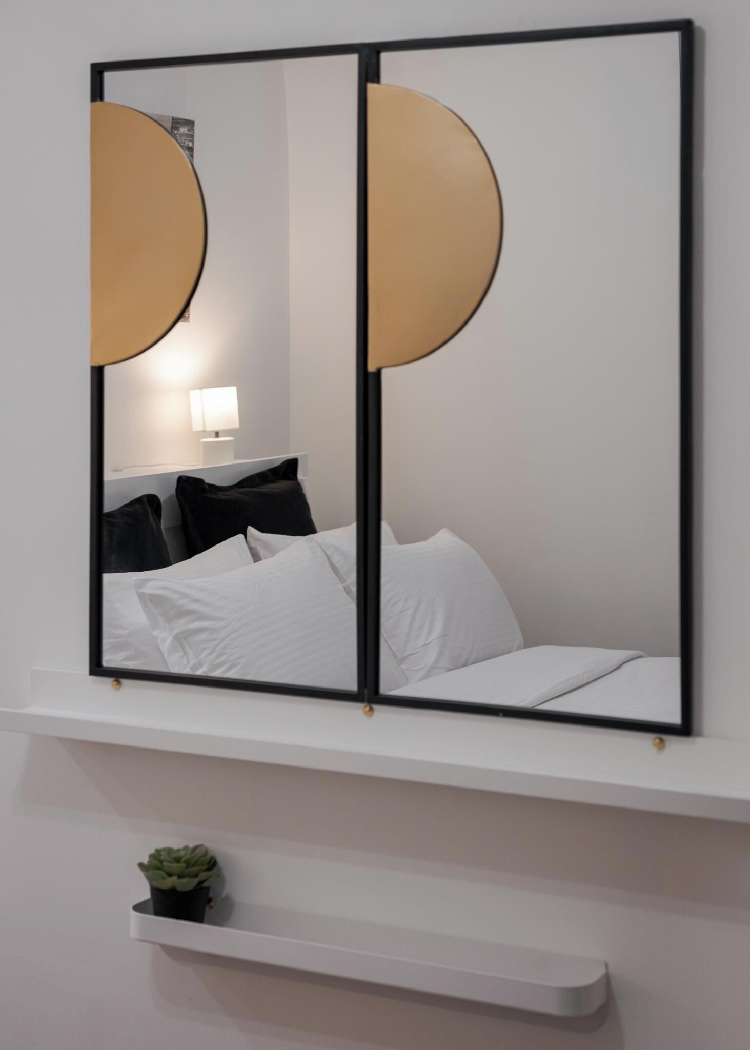 Une chambre à coucher avec un lit, une lampe de chevet et une petite plante en pot.