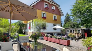 Ein Patio mit Gartenmöbeln, einem Tisch mit Glasplatte und einem großen Sonnenschirm.