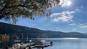 Seeblick mit Steg, Booten und Personen.