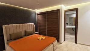 Een moderne slaapkamer met een groot bed, een inloopkast en een badkamer die door een open deur zichtbaar is.
