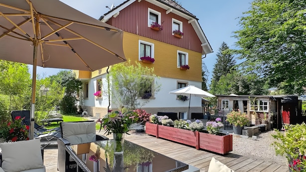 Ein Patio mit Gartenmöbeln, einem Tisch mit Glasplatte und einem großen Sonnenschirm.
