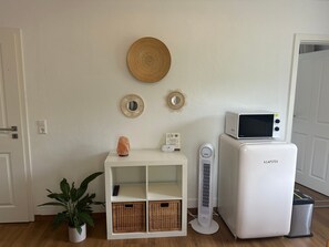 A room with a white cabinet, a small heater, a microwave, and a potted plant.