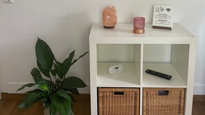 Ein weißer Beistelltisch mit einer Salzlampen, einer rosa Kerze und einem Schild mit den Wörtern 'network' und 'password'.