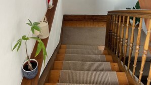 Eine Treppe mit Holzwangen, ein Bücherregal mit Büchern, ein gerahmtes Bild und ein Blumentopf.