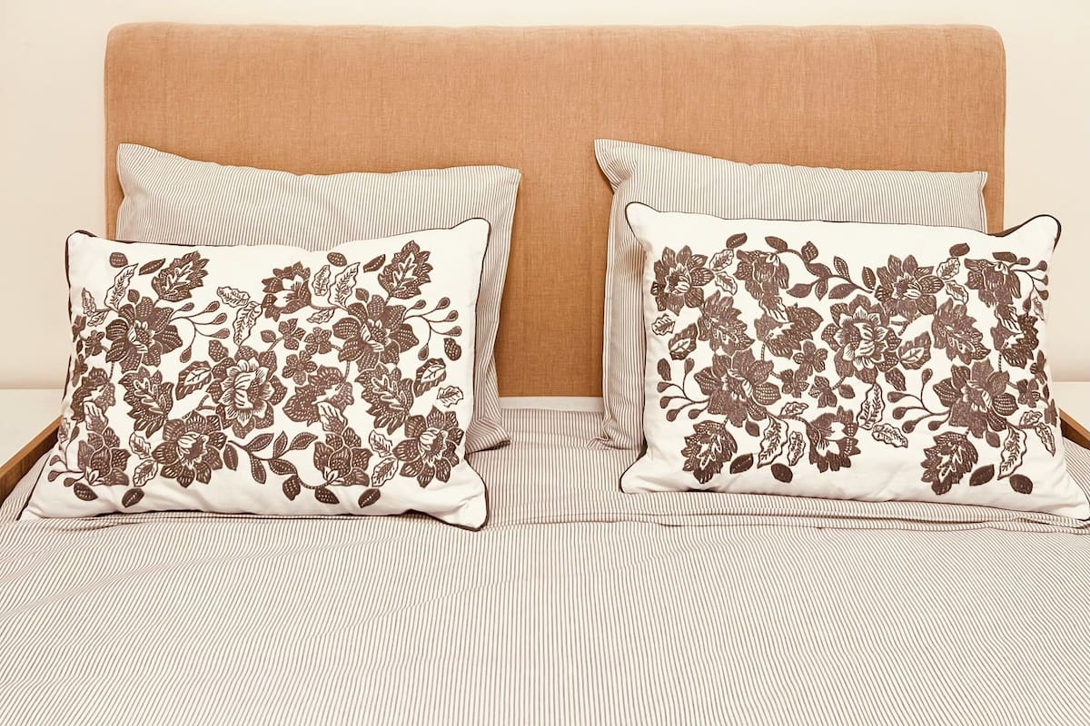 A bed with two pillows, a striped bedspread, and a plain headboard.