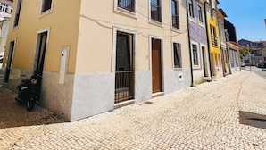 A multi-story building with a yellow facade, large windows, and a tiled pavement in front. - Rabumba - Aveiro Central Lodging (Aveiro)